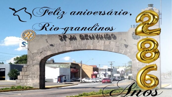 Pórtico de rio grande dizendo Feliz aniversário Rio grande, com uma silhueta de uma cuia de chimarrão e 3 balões dourados formando o numero 286