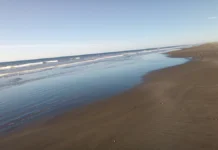 Praia do Cassino Orla do mar. À esquerda o oceano e a esquerda areia da praia. Céu azul sem nuvens