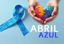 Abril Azul: Mês da Conscientização do Autismo em Rio Grande Um laço azul ao lado de duas mãos segurando um coração feito de quebra-cabeça colorido. Abaixo da mão a palavra abril em letras brancas e a palavra azul na cor azul forte. O fundo é azul claro.